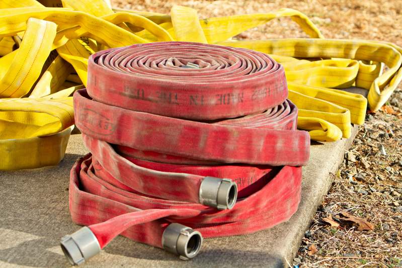 Close-up of a coiled premium garden hose being pressure-tested on grass with measuring tools nearby