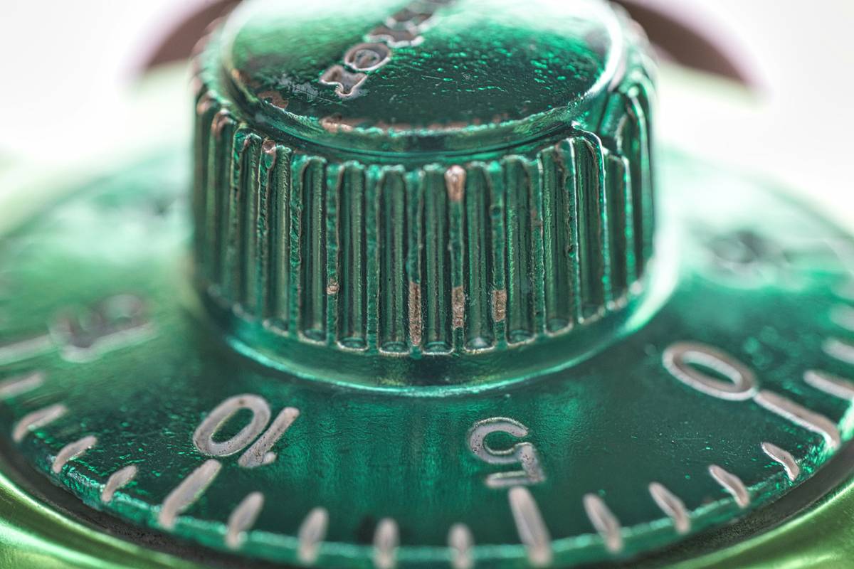 expert gardener garden hose timer connected to a brass spigot, brass fittings, and a coiled expandable garden hose in a sunlit backyard